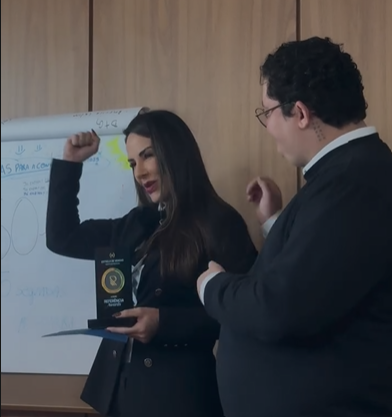 Amanda entregando placa de referência a aluno